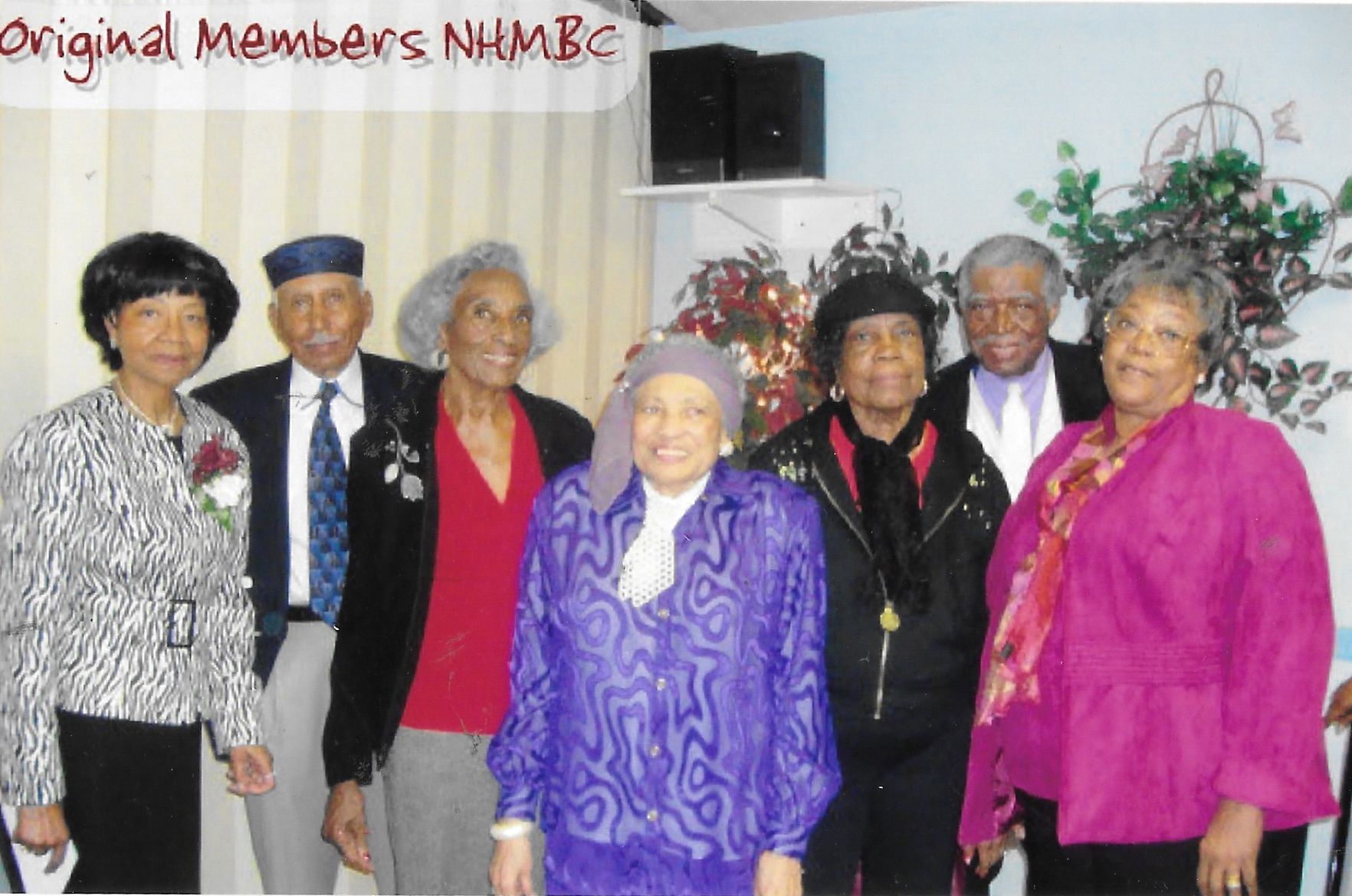 Six people posing indoors, labeled “Original Members,” with Christmas decorations in the background