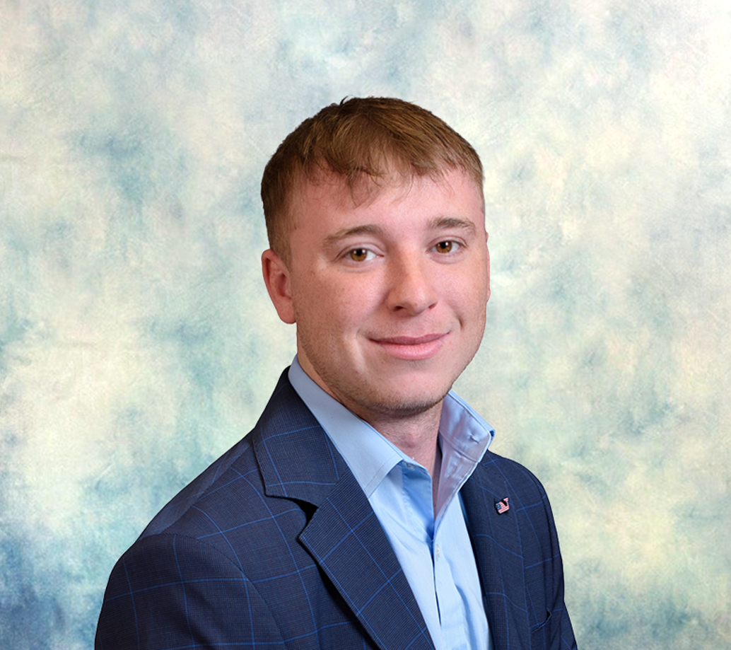 Portrait of a man in a blue suit jacket and light blue shirt against a soft painted backdrop