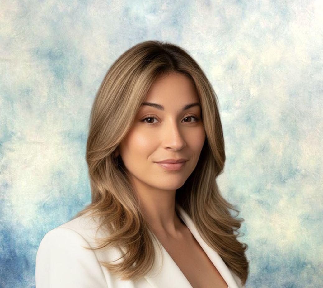 Studio portrait of a woman in a white blazer, smiling against a soft blue background