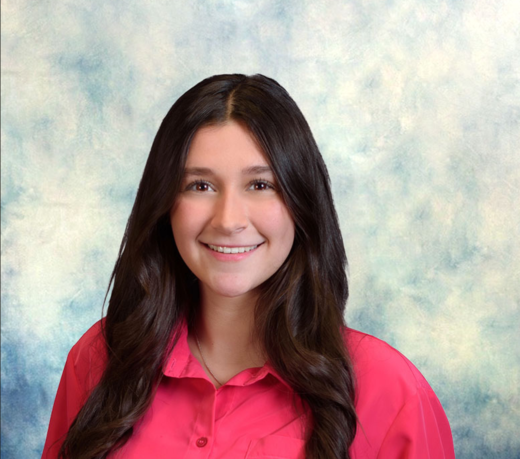 Smiling person in a bright pink shirt against a soft blue studio backdrop