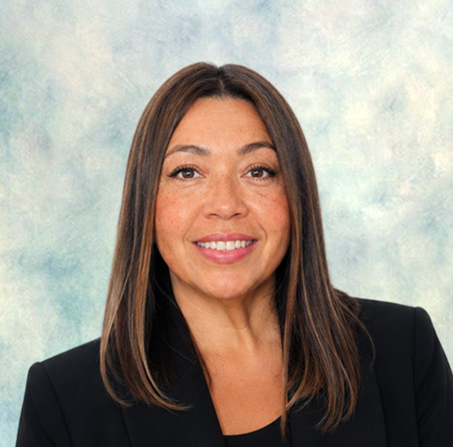 Smiling woman with long brown hair in a black blazer against a white background