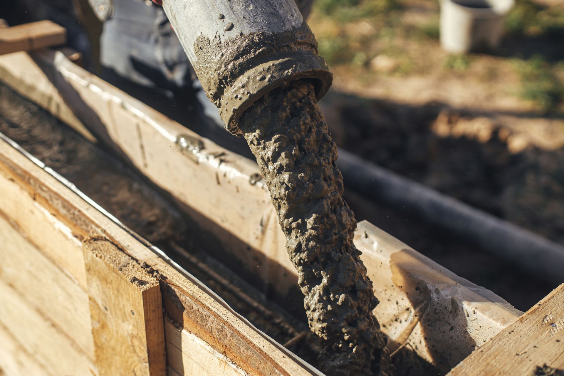 A person is pouring concrete into a wooden box.