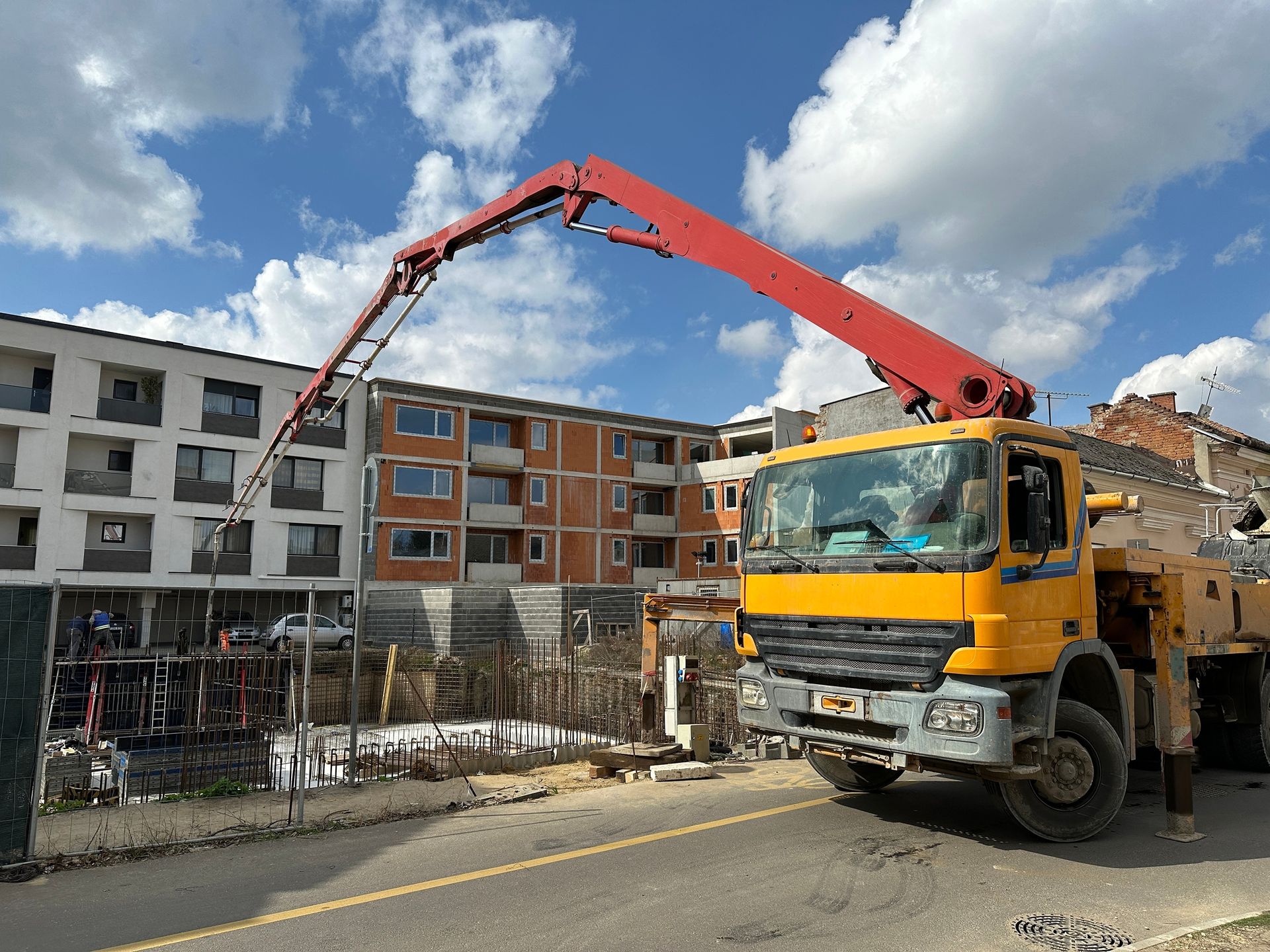 A yellow and red concrete pump truck is parked on the side of the road.
