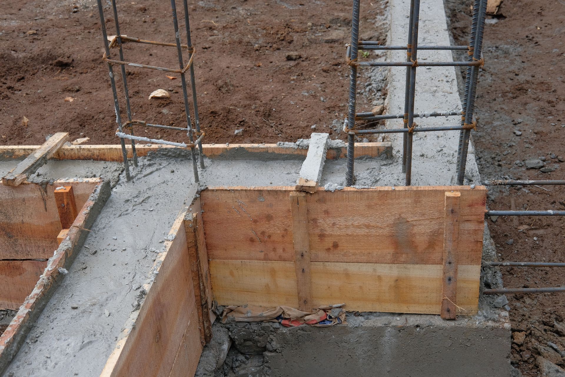 A concrete foundation is being built with wooden forms and steel bars.