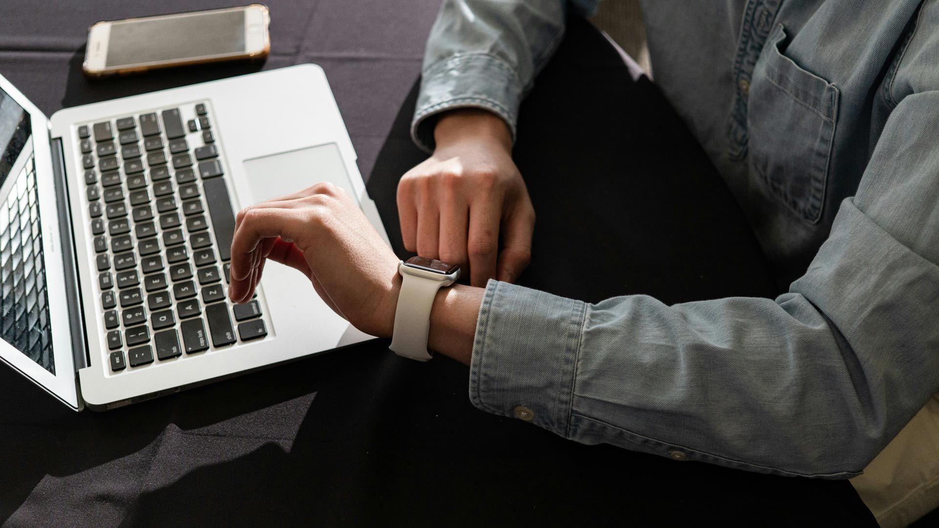 Busy executive checking the time while sitting at a laptop trying to conduct an executive job hunt