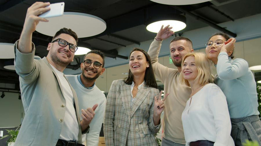 Group of professionally dressed colleagues smiling for a selfie at a holiday networking gathering