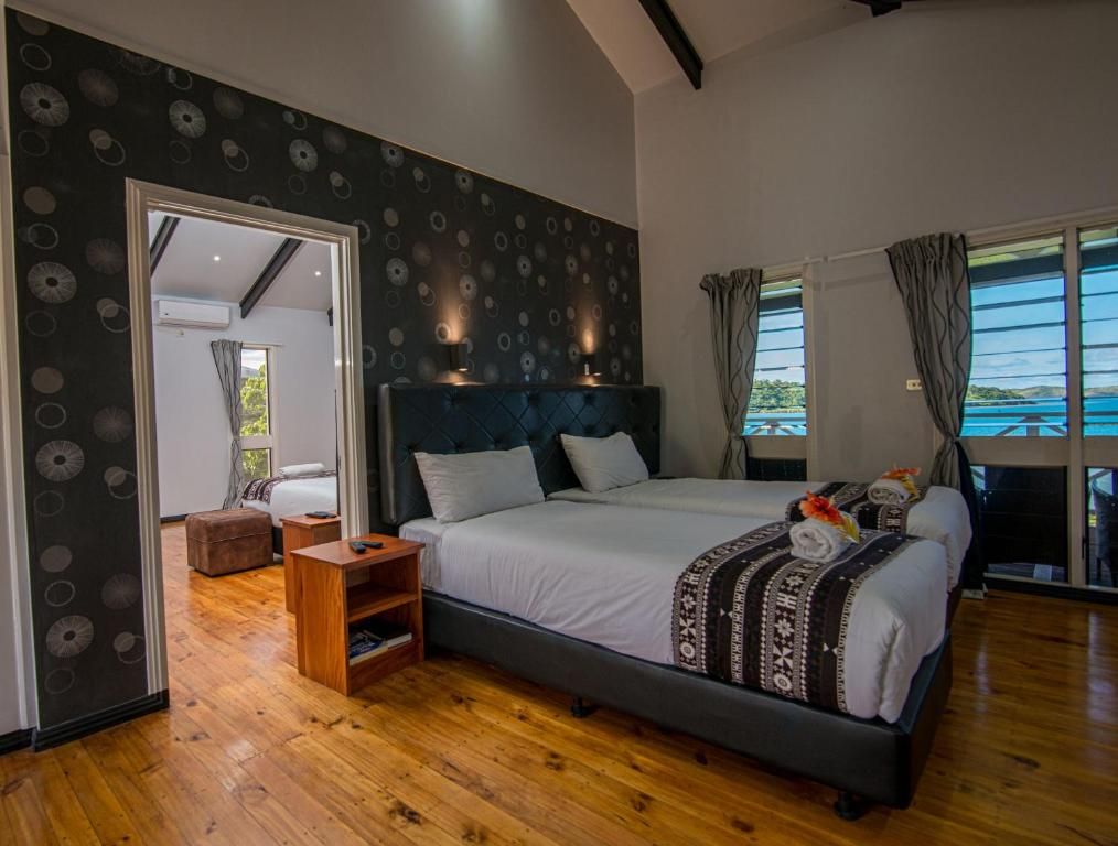 Modern bedroom with a king bed, patterned wallpaper, wooden floor, and large windows with curtains
