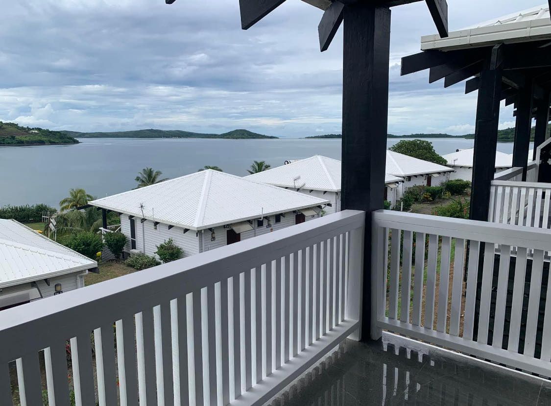 Balcony overlooking a lake and white-roofed buildings under a cloudy sky