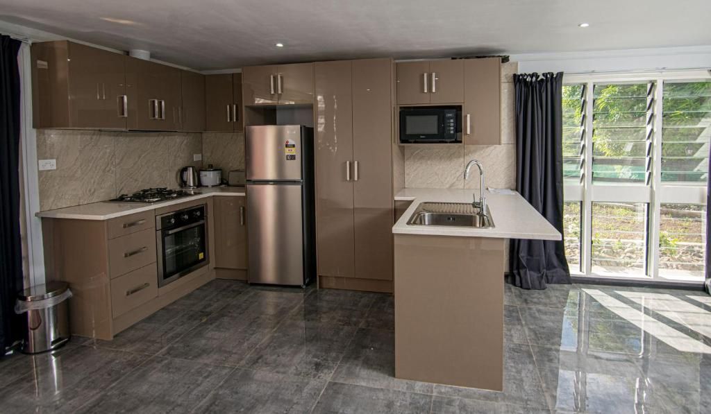 Modern kitchen with brown cabinets, stainless appliances, marble island, and sliding glass doors to a patio.