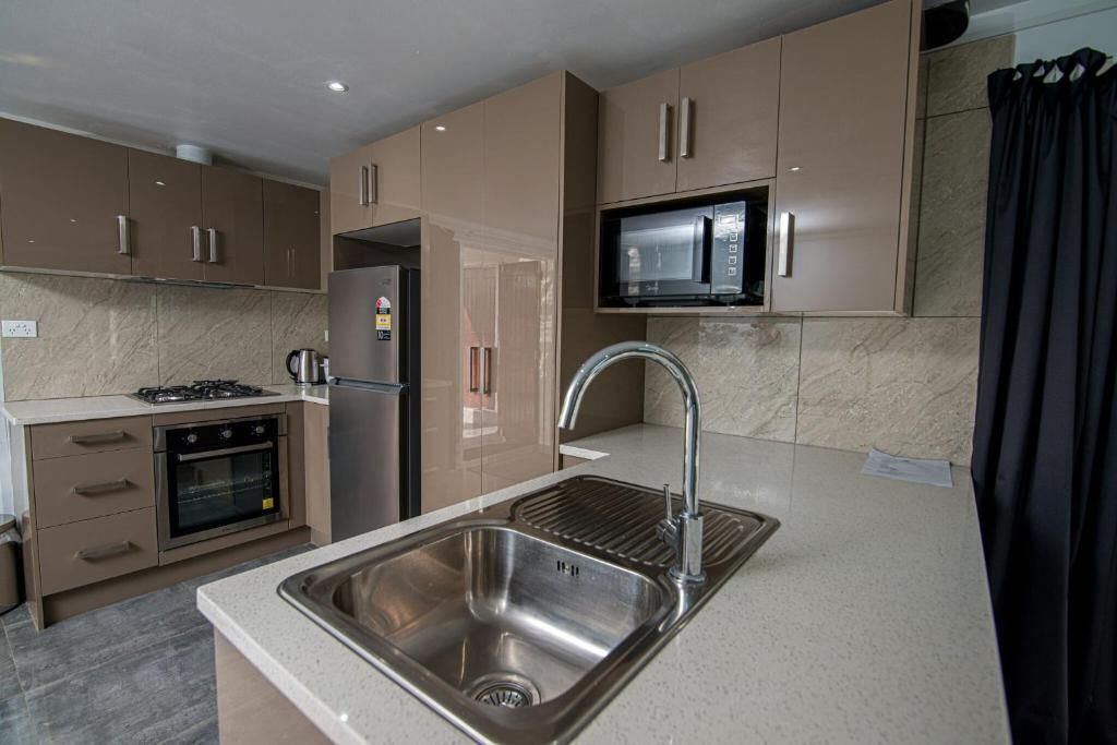 Modern kitchen with beige cabinets, stainless steel appliances, and a sink on a gray island countertop
