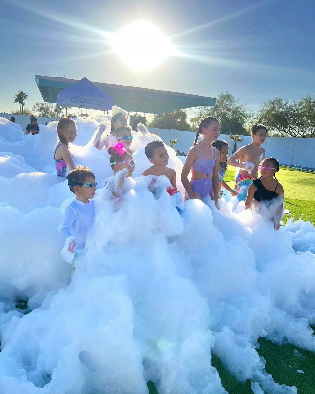 Children playing in a large foam pile outdoors on a sunny day