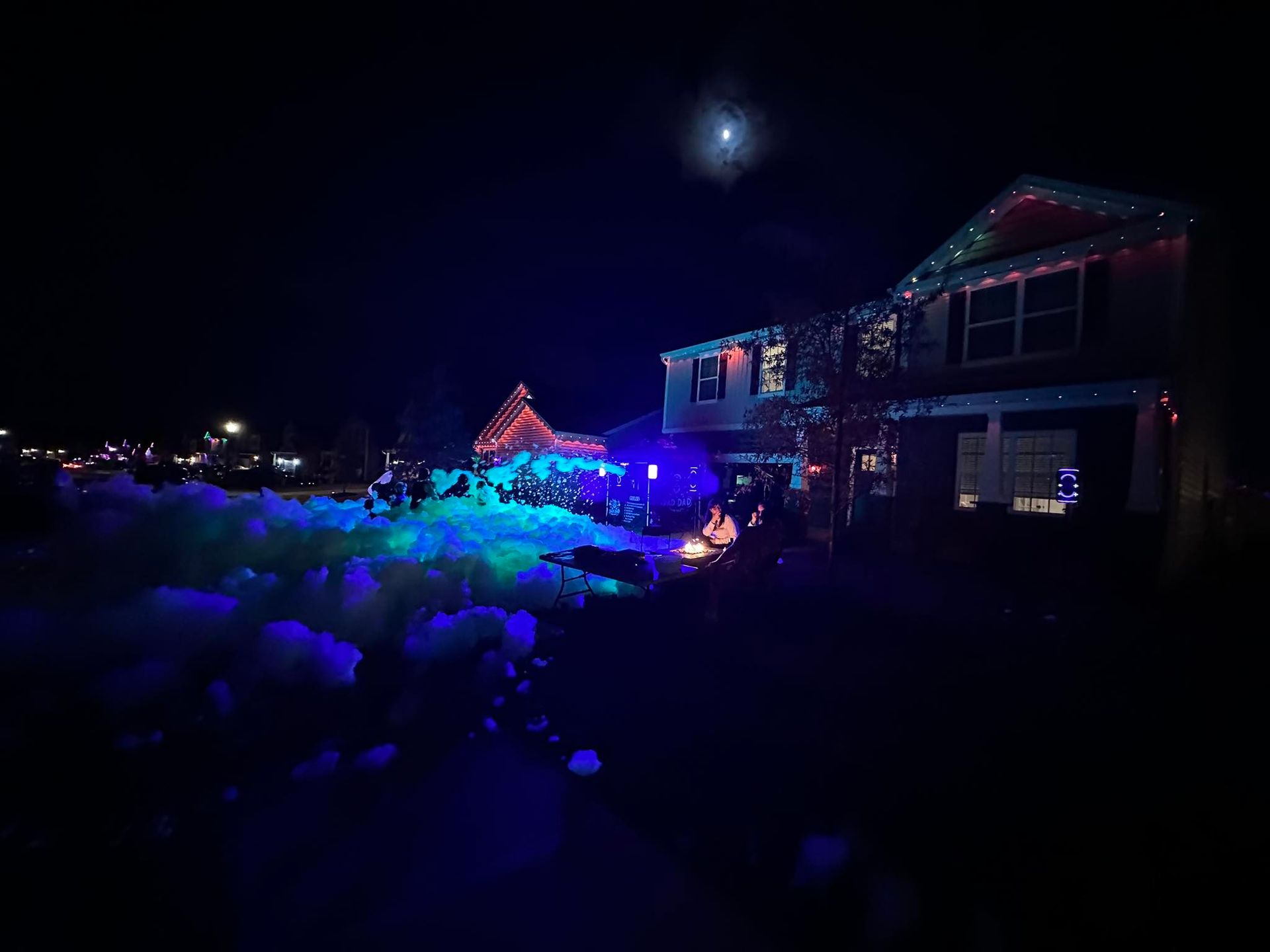House and yard lit with blue and purple Christmas lights at night