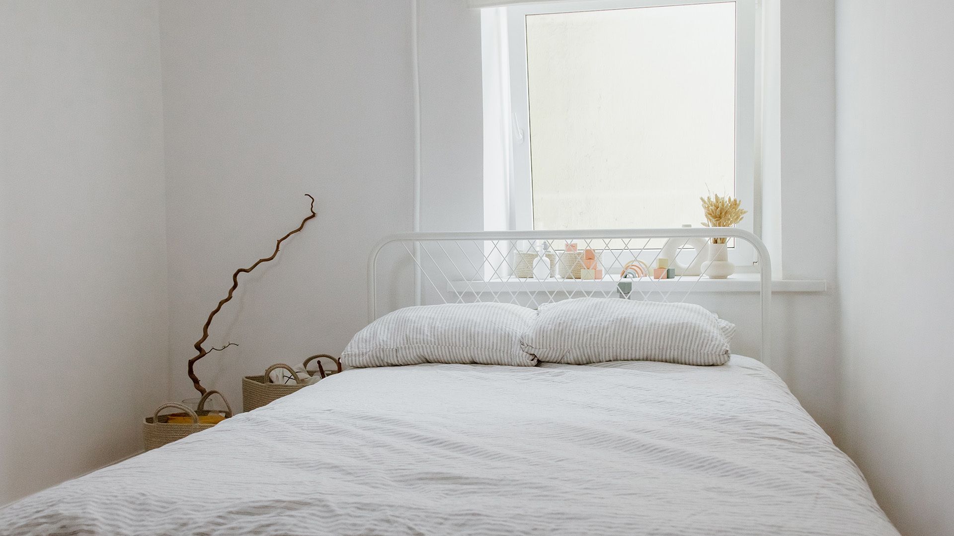 White bedroom with bed, window, and decorative items.