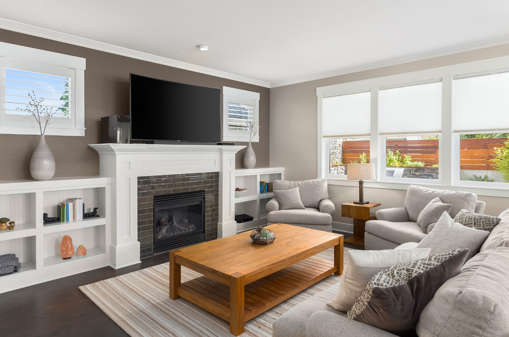 Modern white living room with a beige sectional sofa, arched windows, and a geometric patterned armchair.