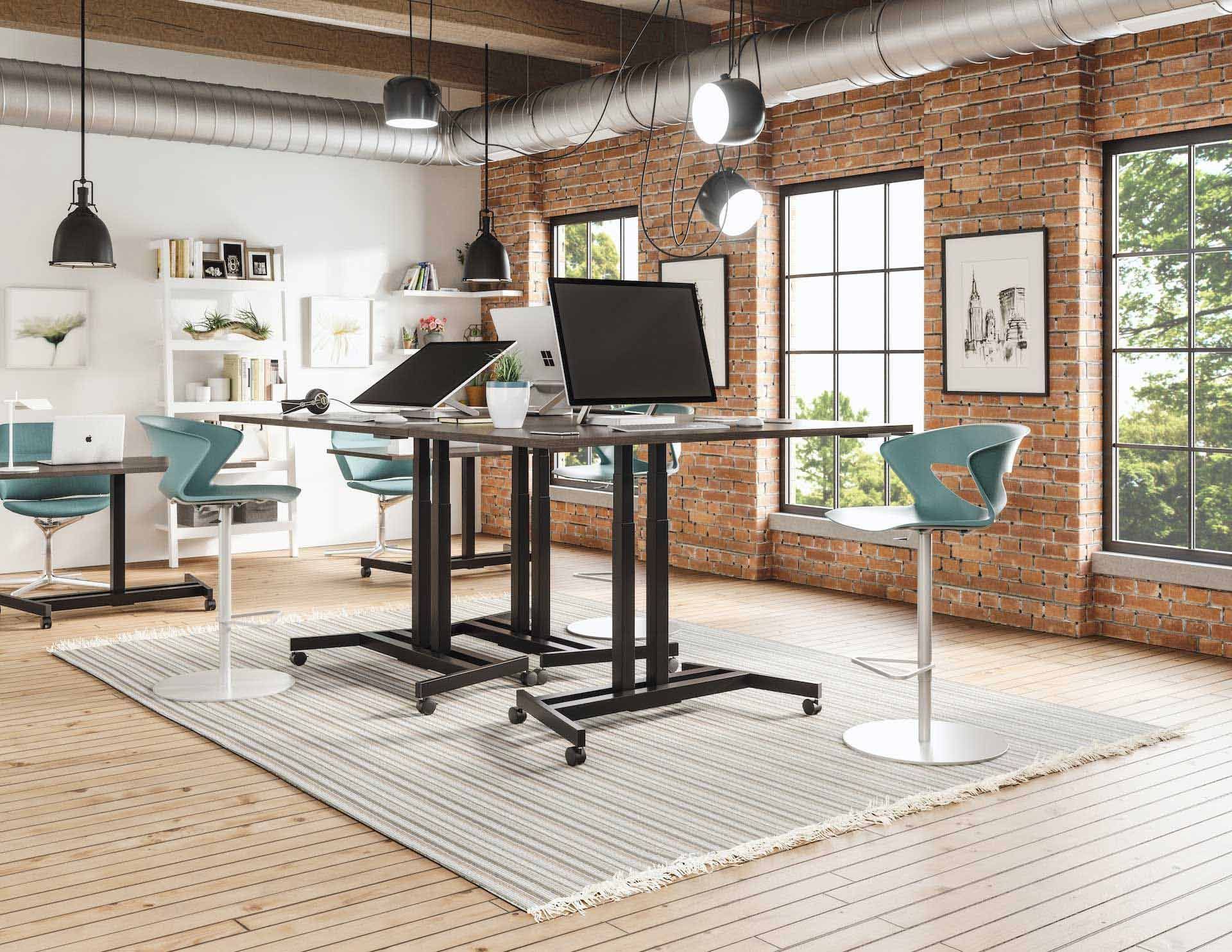 Modern office space with sit-stand desks, exposed brick, and chairs.
