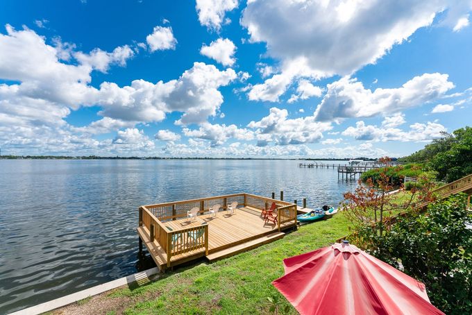 A large body of water with a dock and a red umbrella in the foreground.