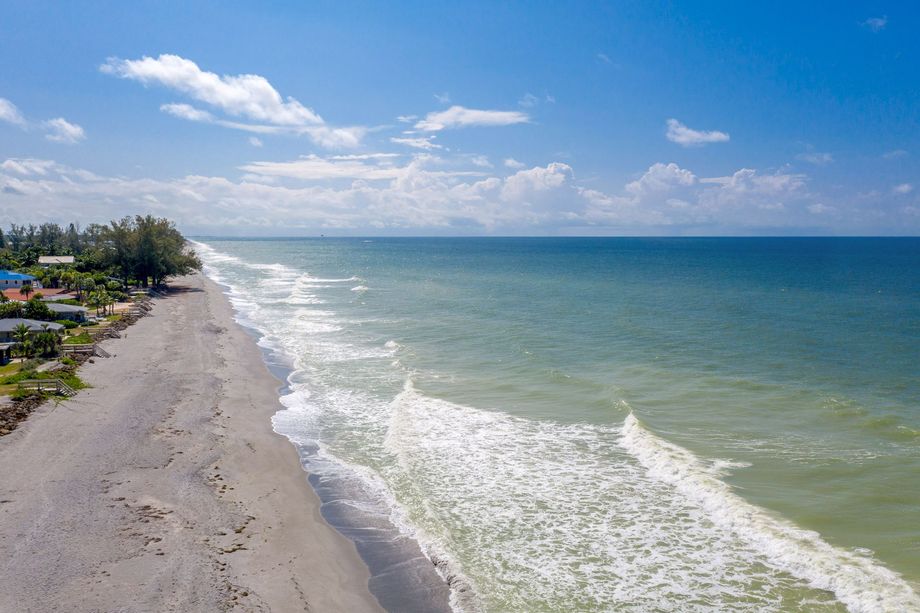 An aerial view of a beach with waves crashing on the shore.