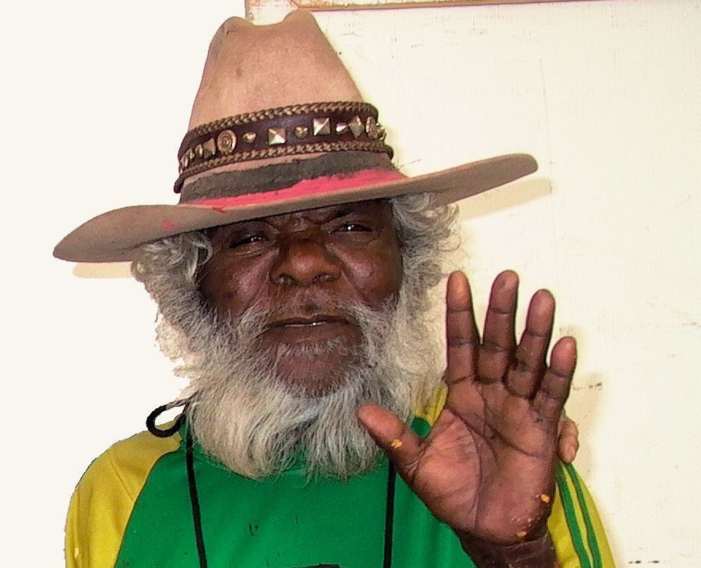 A man with a beard wearing a hat and a green shirt