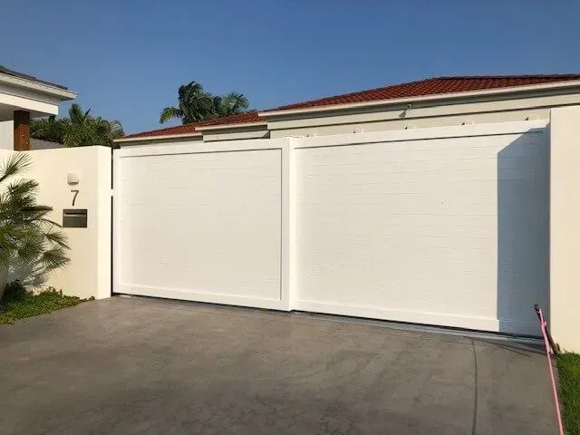 A White Sliding Gate is Sitting in Front of a House — Sunshine Gates in Kunda Park, QLD