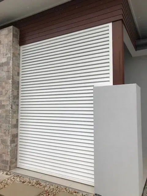 A White Garage Door is Sitting on the Side of a House — Sunshine Gates in Kunda Park, QLD