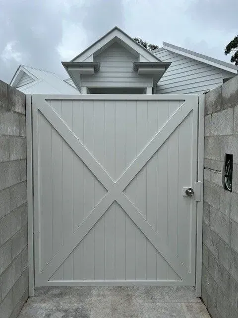 A White Gate is Between Two Brick Walls in Front of a House — Sunshine Gates in Mooloolaba, QLD