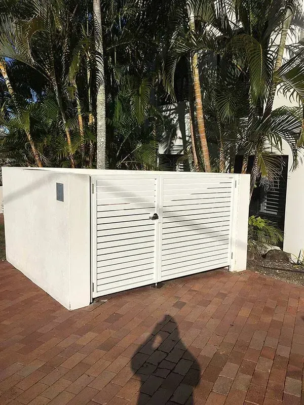 A White Fence is Sitting on Top of a Brick Driveway Next to a Palm Tree — Sunshine Gates in Kunda Park, QLD