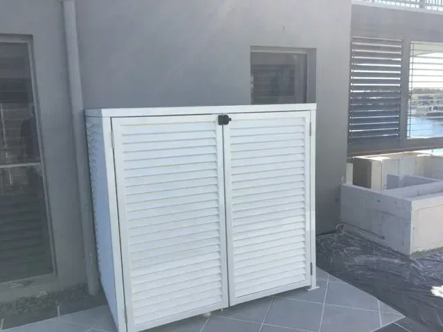 A White Cabinet With Shutters on the Doors is Sitting Outside of a Building — Sunshine Gates in Kunda Park, QLD