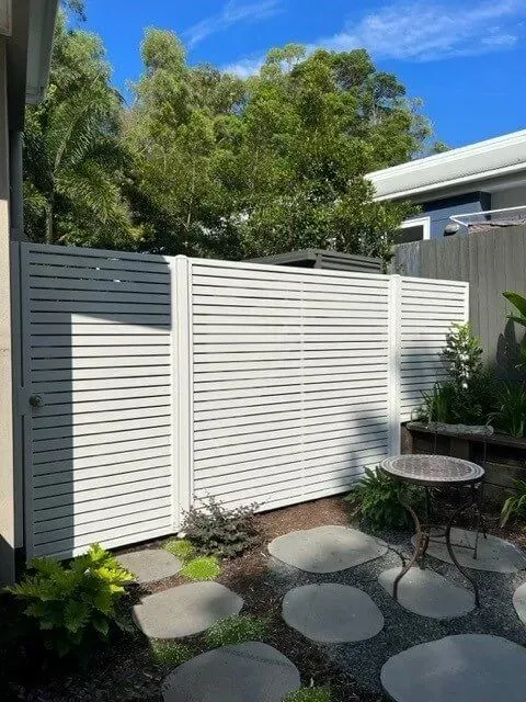 A White Fence Surrounds a Garden With a Table in the Middle of It — Sunshine Gates in Kunda Park, QLD