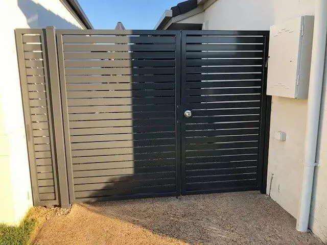 A Black Fence With a Door is Next to a House — Sunshine Gates in Kunda Park, QLD