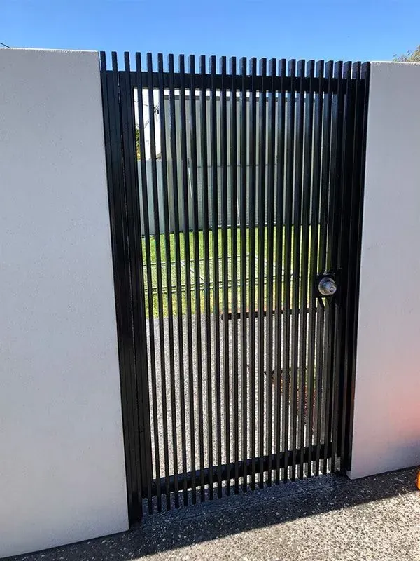 A Black Gate is Sitting Next to a White Wall — Sunshine Gates in Kunda Park, QLD