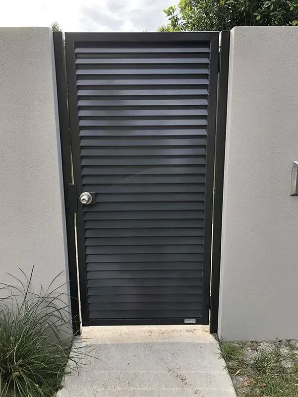 A Black Gate is Sitting Next to a White Wall — Sunshine Gates in Kunda Park, QLD