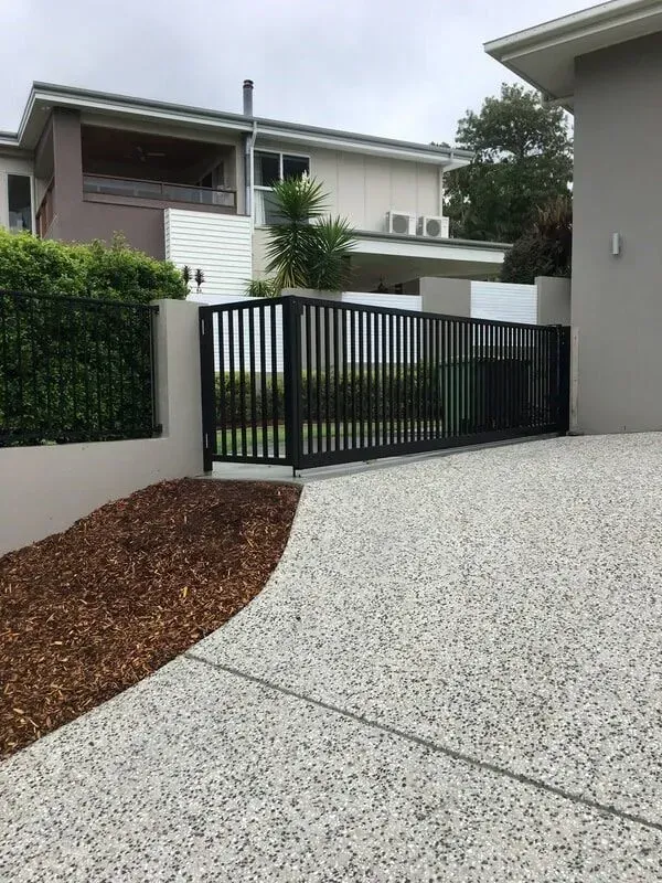 A Driveway With a Fence and a House in the Background — Sunshine Gates in Kunda Park, QLD