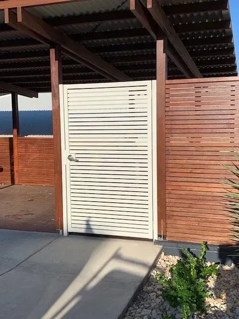 A White Gate With a Wooden Fence Behind It — Sunshine Gates in Kunda Park, QLD