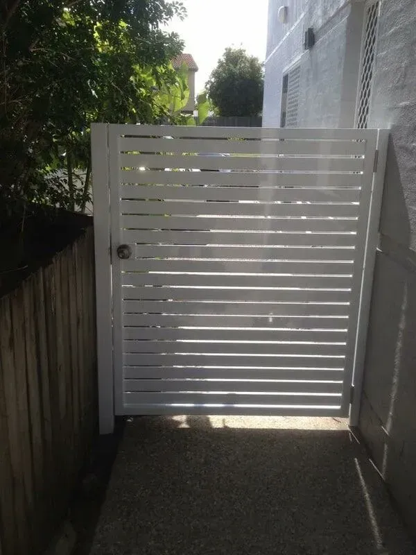 A White Gate With a Wooden Fence Behind It — Sunshine Gates in Kunda Park, QLD