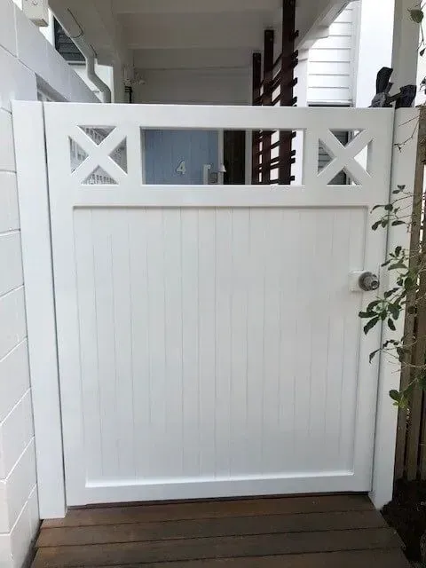 A White Gate is Sitting on a Wooden Deck Next to a Building — Sunshine Gates in Kunda Park, QLD