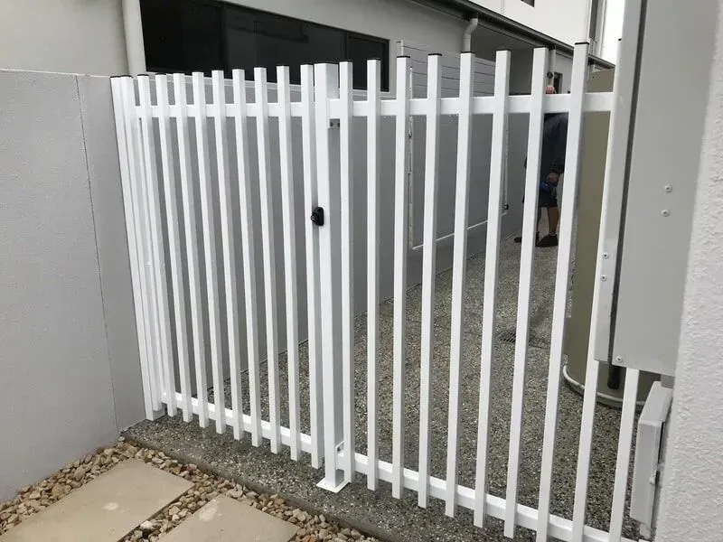 A White Fence With a Gate is Sitting Next to a Building — Sunshine Gates in Kunda Park, QLD