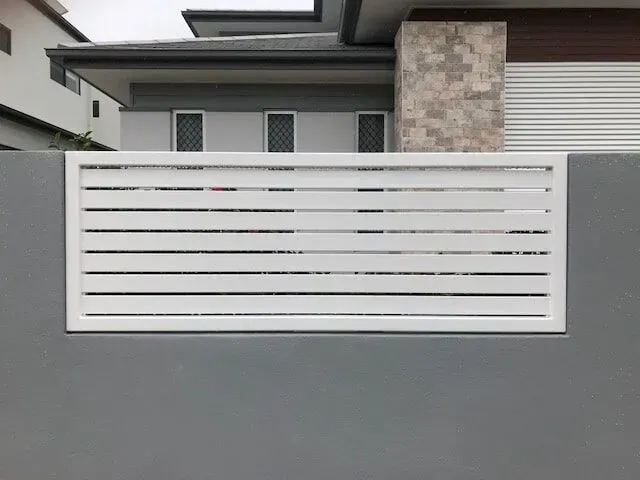 A White Fence is Sitting on Top of a Gray Wall in Front of a House — Sunshine Gates in Kunda Park, QLD