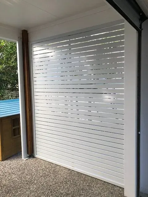 A White Garage Door With a Blue Roof is Sitting on a Porch — Sunshine Gates in Kunda Park, QLD