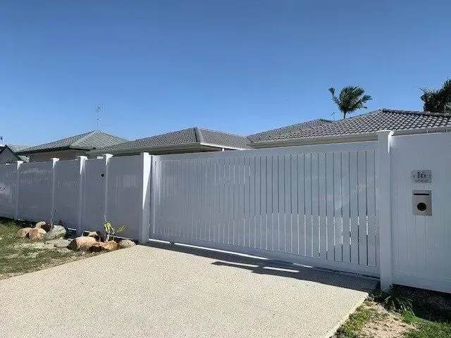 A White Fence is Surrounding a House With a Sliding Gate — Sunshine Gates in Kunda Park, QLD