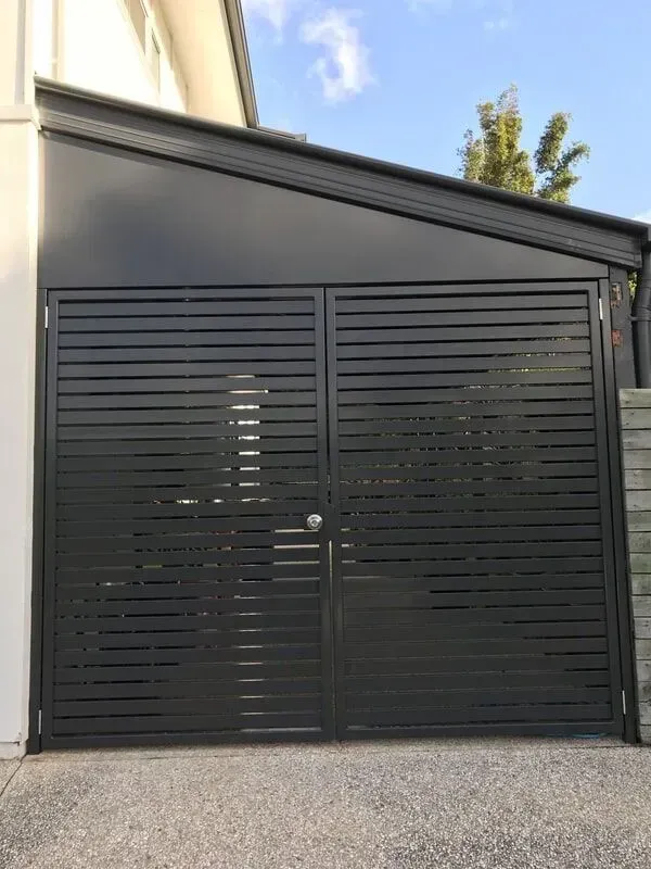 A Black Garage Door is Sitting Next to a White House — Sunshine Gates in Kunda Park, QLD