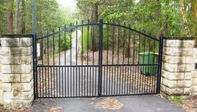 A Black Wrought Iron Gate is Open to a Driveway Surrounded by Trees — Sunshine Gates in Kunda Park, QLD