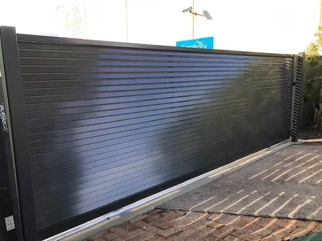 A Black Fence is Sitting on Top of a Brick Driveway — Sunshine Gates in Kunda Park, QLD