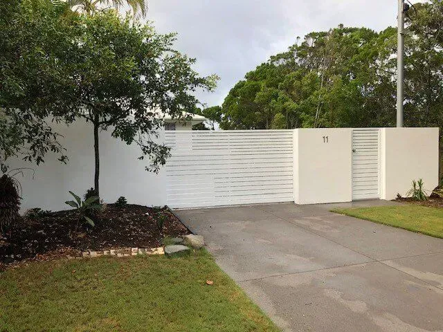 A Black Fence is Sitting on Top of a Brick Driveway — Sunshine Gates in Kunda Park, QLD