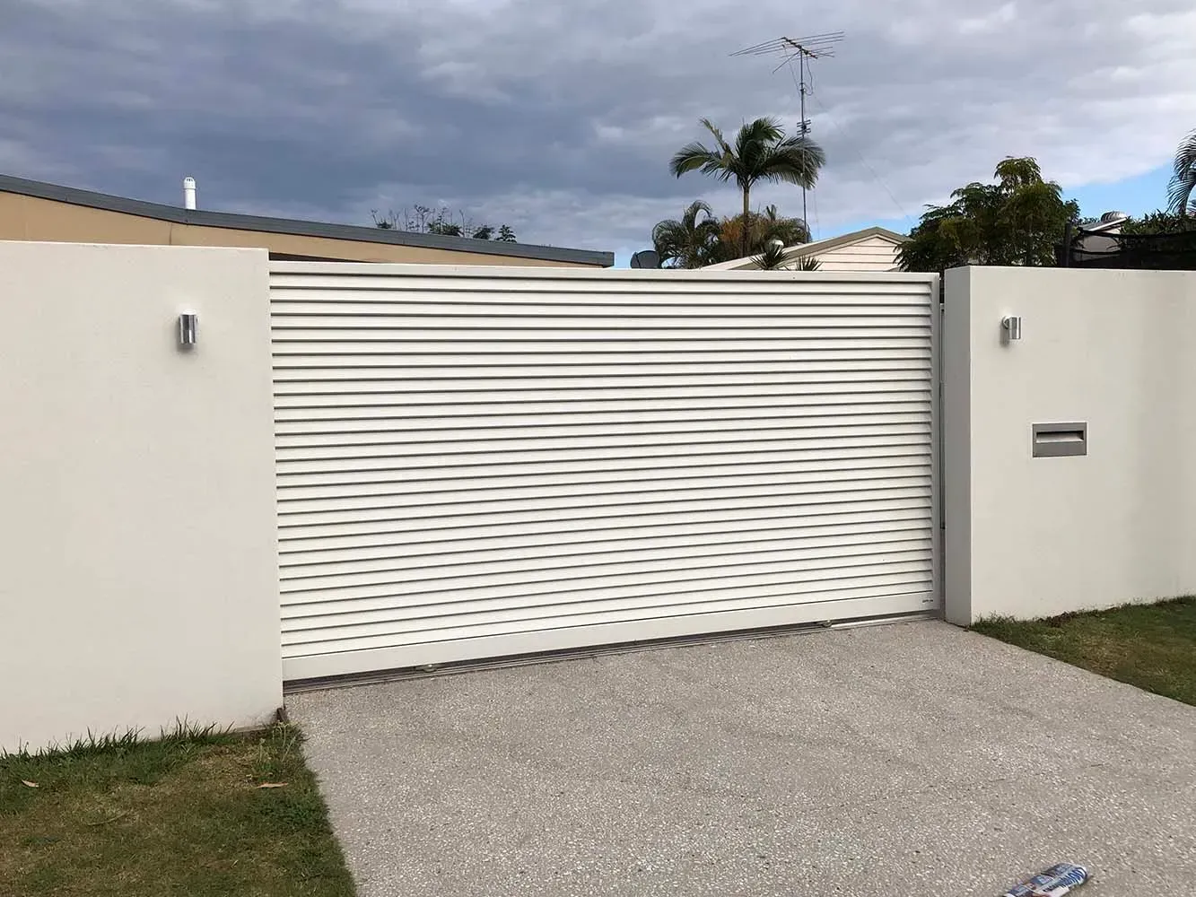 A White Fence With a Sliding Gate in Front of a House — Sunshine Gates in Kunda Park, QLD