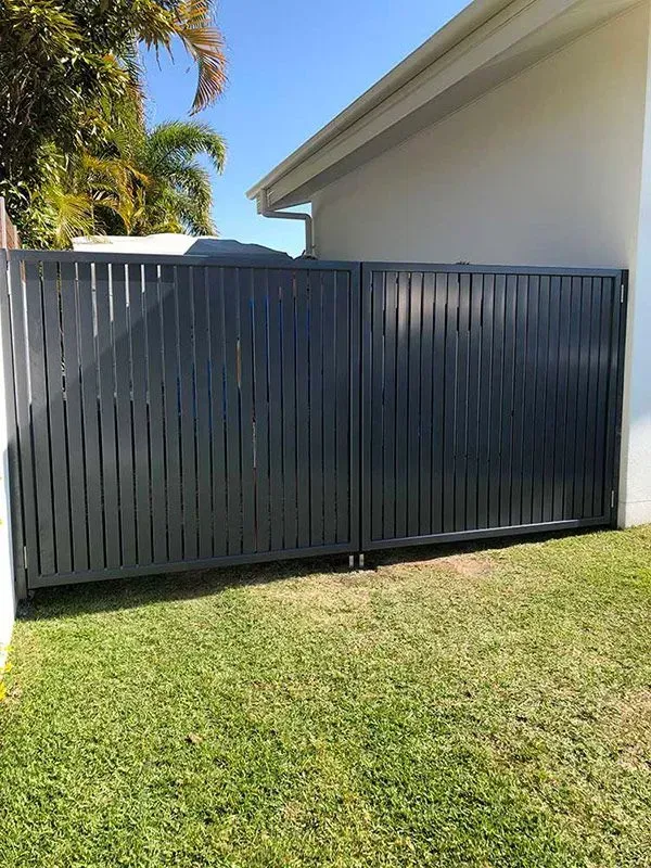 A Black Fence is Sitting in the Grass in Front of a House — Sunshine Gates in Kunda Park, QLD