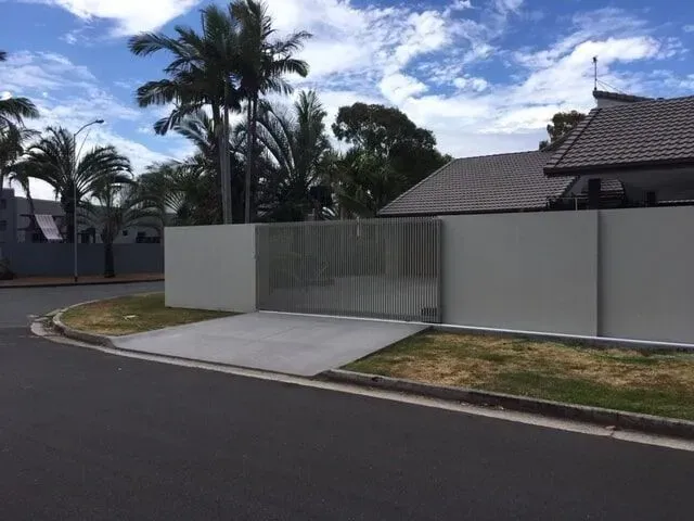 A White Fence Surrounds a House With Palm Trees in the Background — Sunshine Gates in Kunda Park, QLD