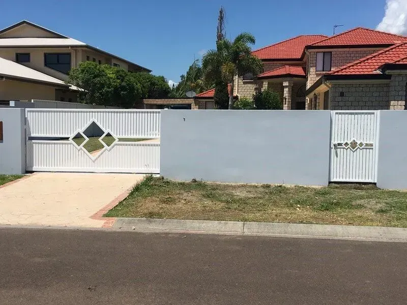 A White Fence With a Sliding Gate in Front of a House — Sunshine Gates in Kunda Park, QLD