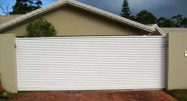 A White Garage Door is Sitting in Front of a House — Sunshine Gates in Kunda Park, QLD