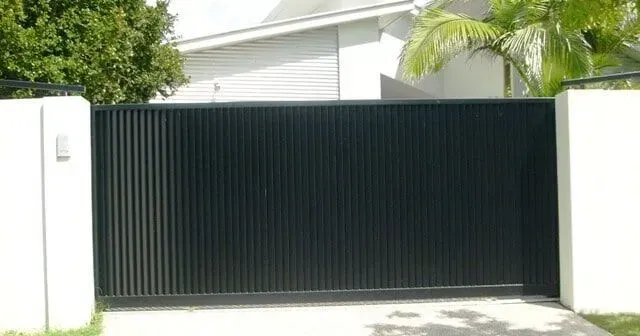 A Black Sliding Gate is Open to a Driveway in Front of a House — Sunshine Gates in Kunda Park, QLD