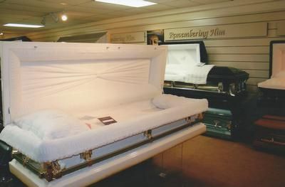Display of white coffins in a funeral home showroom
